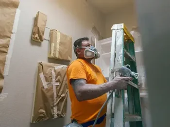 PaintMor Painters professional residential interior painters in Prosper showing our painter applying tan paint with a sprayer in a walk-in closet.