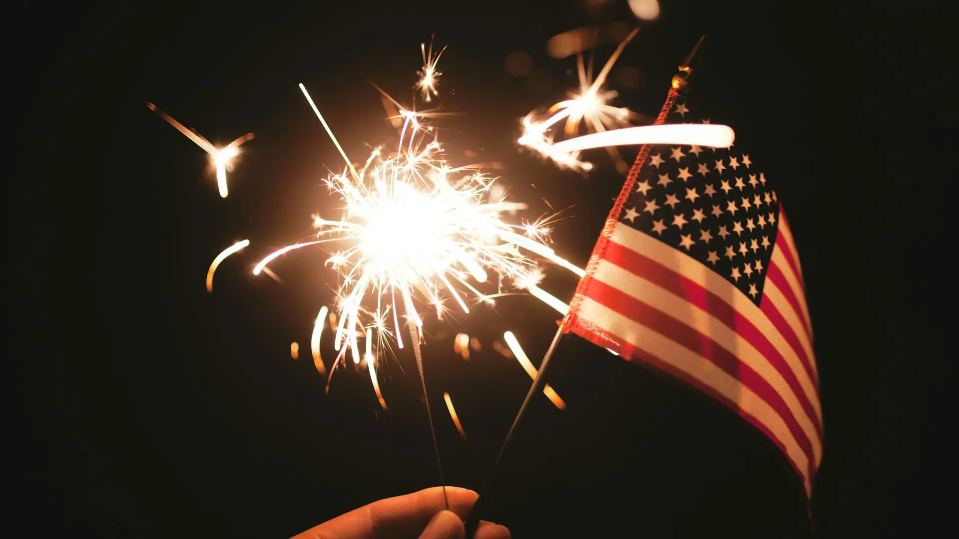 Fourth of July home hosting tips for North Texas family and friends with outdoor sparkler and flag.