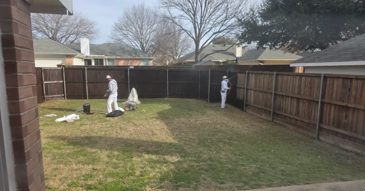 Paintmor blog featured image of workers staining a wooden fence dark brown in spring