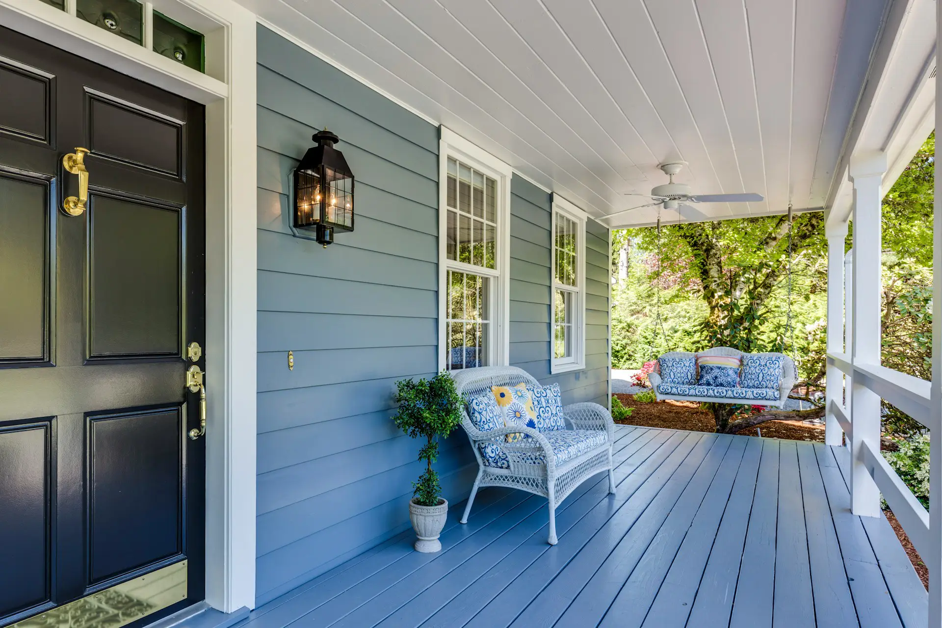 a painted porch with a bench and a swing showing exterior painting trends. Photo by Francesca Tosolini on Unsplash