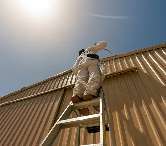 A PaintMor painter on a ladder painting the exterior of a religious facility in Dallas.