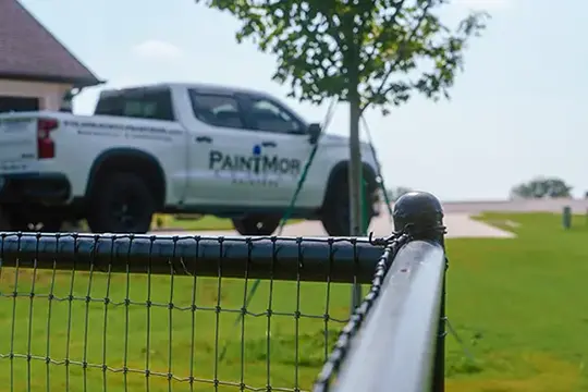 PaintMor Painters professional fence painting and staining, image of black painted metal fence with the PaintMor Painters white truck.