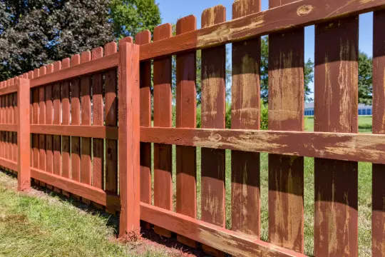 PaintMor Painters professional fence stainers and painters in Plano showing a brown wooden fence partially painted to illustrate the dirfference.