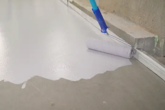 PaintMor Painters professional garage floor epoxy and painting services in Prosper, showing a garage floor with white epoxy being applied to it.