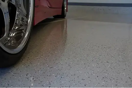 PaintMor Painters professional garage floor epoxy and painting services in McKinney, showing grey and black epoxy on a garage floor with a red sports car.