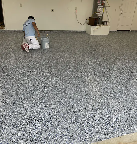 PaintMor Painters worker applying epoxy garage floor coating in North Dallas.