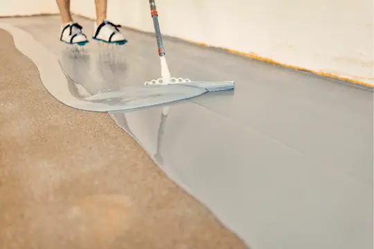 PaintMor Painters proffesional garage floor epoxy and painting services in Carrollton, showing the application of epoxy on a garage floor.