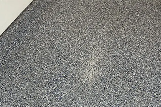 PaintMor Painters professional garage floor expoy painters in Frisco showing a close up shot of a grey and black speckled epoxy on a garage floor.